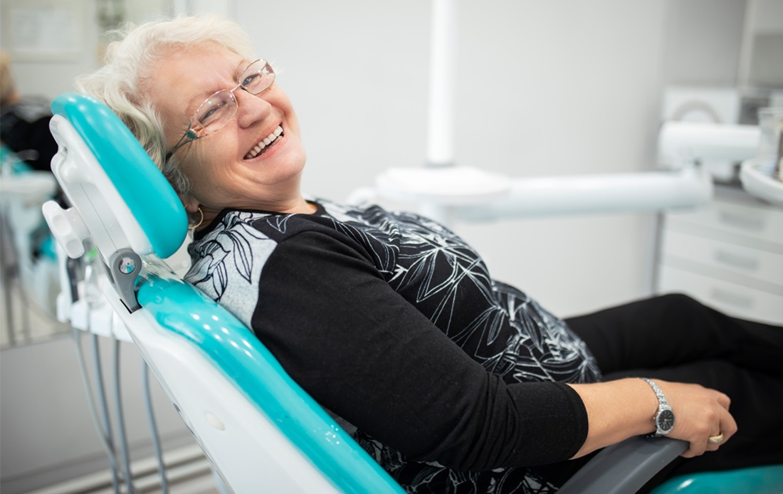 A woman sitting in a dentist chair, smiling.