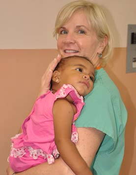 Clinician with young girl in her arms