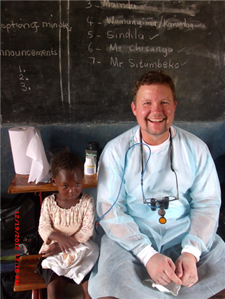 Dentist sitting with small child in classroom 