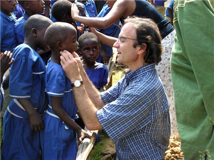 Volunteer kneeling down examining child's mouth outside