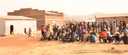 Photo of a group of people on a dusty landscape with buildings